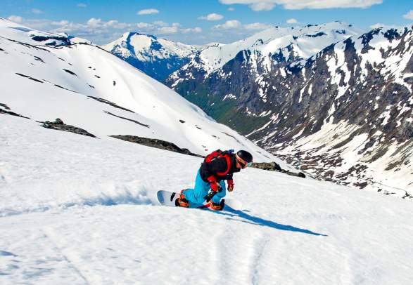 En person står på snowboard ned fjellsiden i Stryn