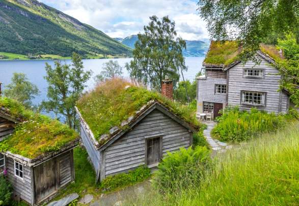 Old wooden houses with grass on the roof at a fjord bank in Jølster