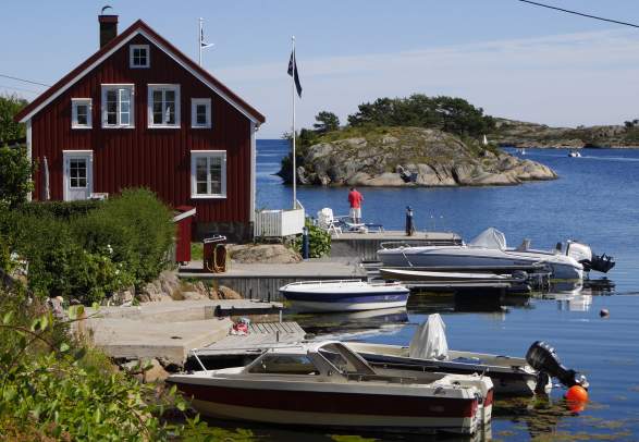 View of a house near the water and a few boats in Sandøya outside of Tvedestrand, Southern Norway