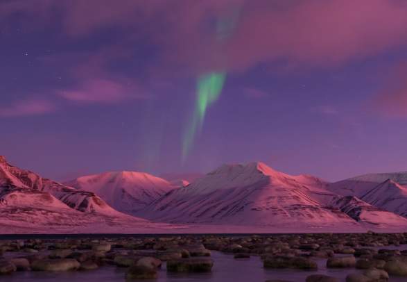 Northern lights and pink sky over snow-covered mountains in Svalbard