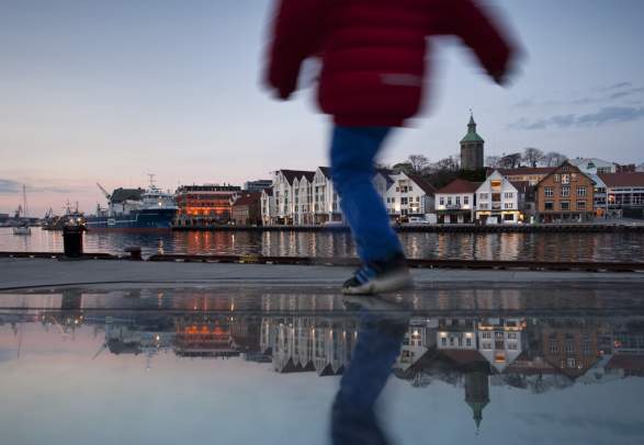 A person running by the wharf with Stavanger as a backdrop in Fjord Norway