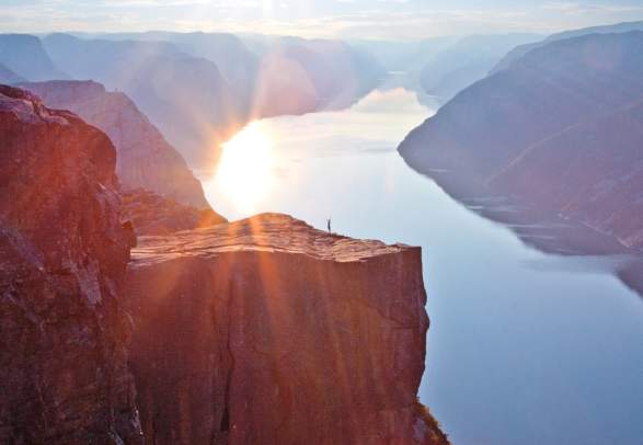 A person standing alone at Preikestolen (The Pulpit Rock) in sunshine