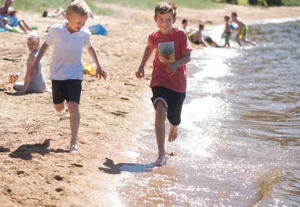 Two children running by the waterline on Kvavik beach in Lyngdal, Southern Norway