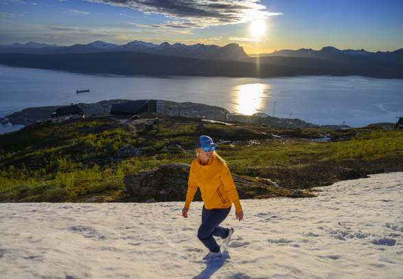 A woman is enjoying a late hike under the midnight sun in Narvik, Northern Norway