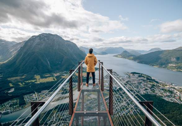 En person på utsiktspunktet Rampestreken ser utover fjorden og fjellene i Åndalsnes i Nordvest på Vestlandet.