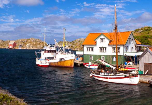 View over a small quay with three boats on a summer day in Røvær