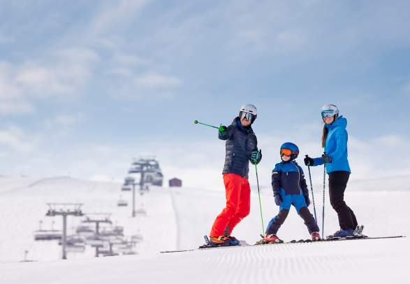 Een gezin van drie aan het skiën op de pistes van de berg Trysilfjellet in Trysil, Oost-Noorwegen.