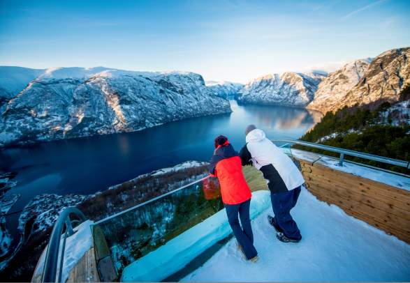 People admiring the view of the Aurlandsfjord from Stegastein viewpoint on Norwegian Scenic Route Aurlandsfjellet in Fjord Norway in winter
