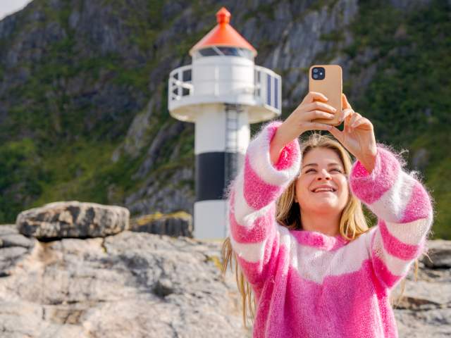 Woman taking a selfie with a lighthouse in Vesterålen, Northern Norway