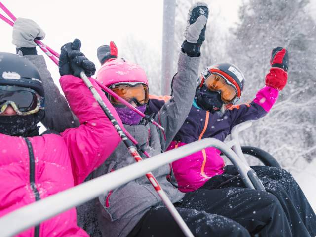 Three happy girls sitting in a ski lift in Geilo ski resort, Eastern Norway