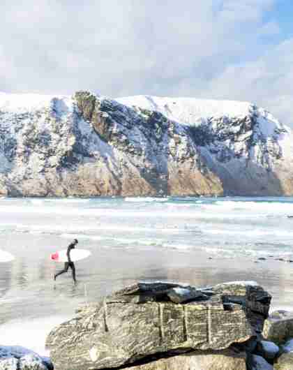 Two surfers walking along the beach in Hoddevik in winter in Fjord Norway