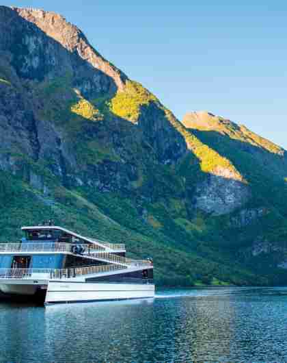 The hybrid electric vessel Vision of the Fjords cruising the Aurlandsfjorden fjord surrounded by mountains