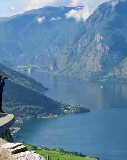 A man standing at a viewpoint taking pictures of the Aurlandsfjord