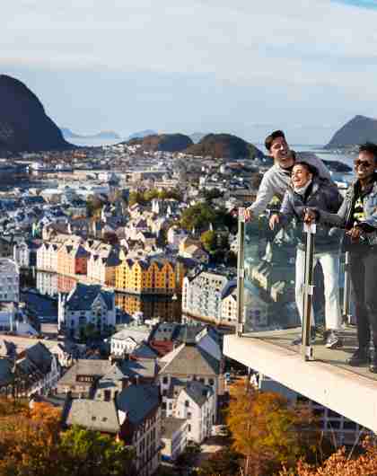 Three people standing on a viewing platform at Mount Aksla in Ålesund, Fjord Norway
