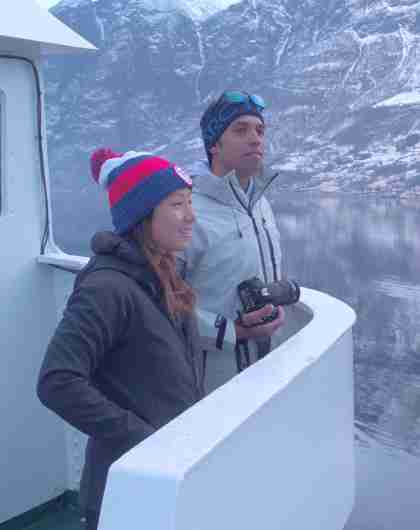 Two people standing on a boat enjoying the view of the Nærøyfjord in winter