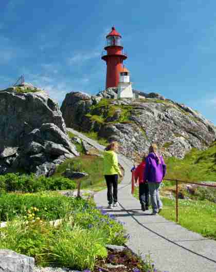People walking towards Ona lighthouse in Møre og Romsdal, Norway