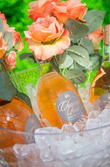 Three bottles of Rose wine on ice and peach colored roses.