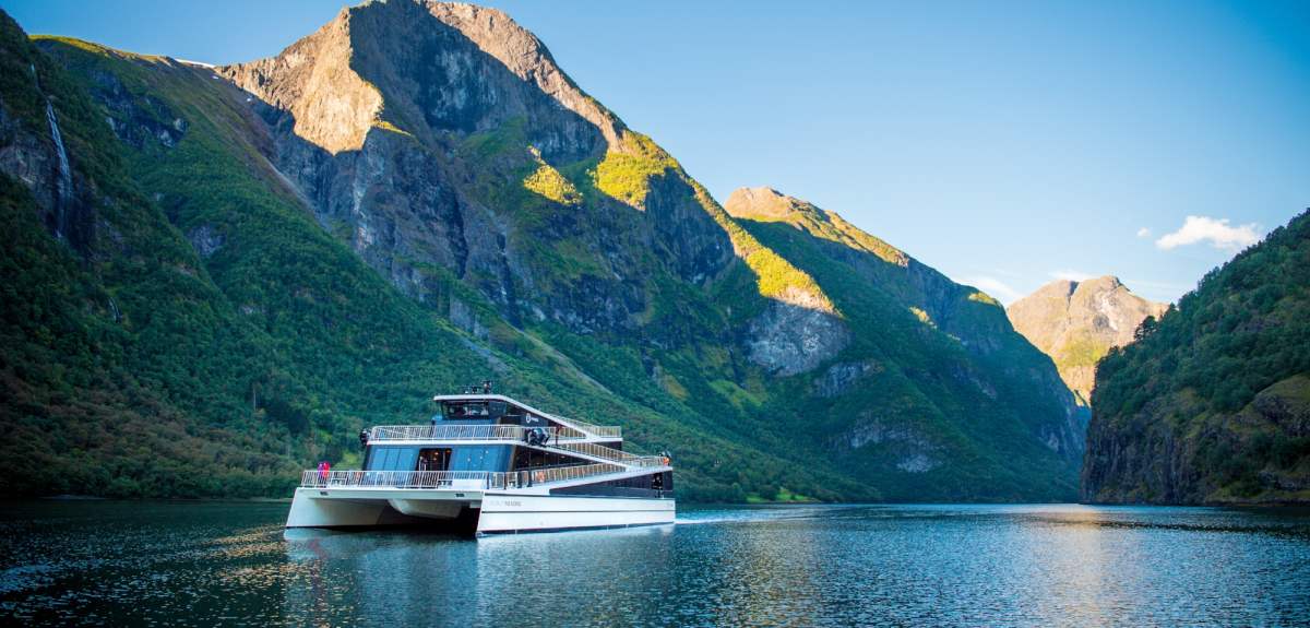 The hybrid electric vessel Vision of the Fjords cruising the Aurlandsfjorden fjord surrounded by mountains