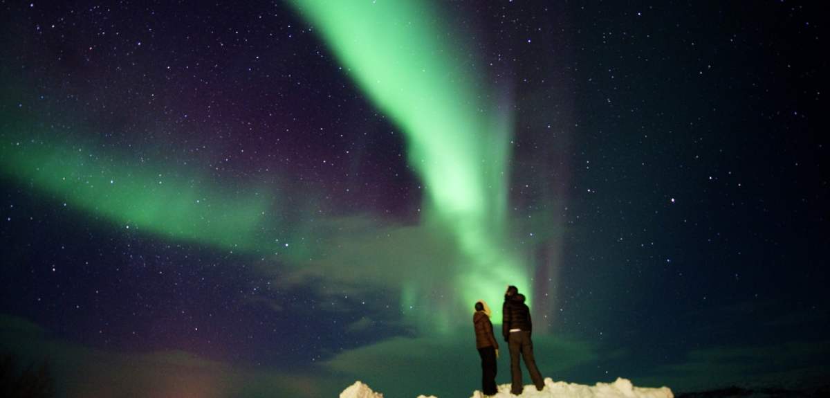 Et par som står og observerer nordlyset i Finnmark