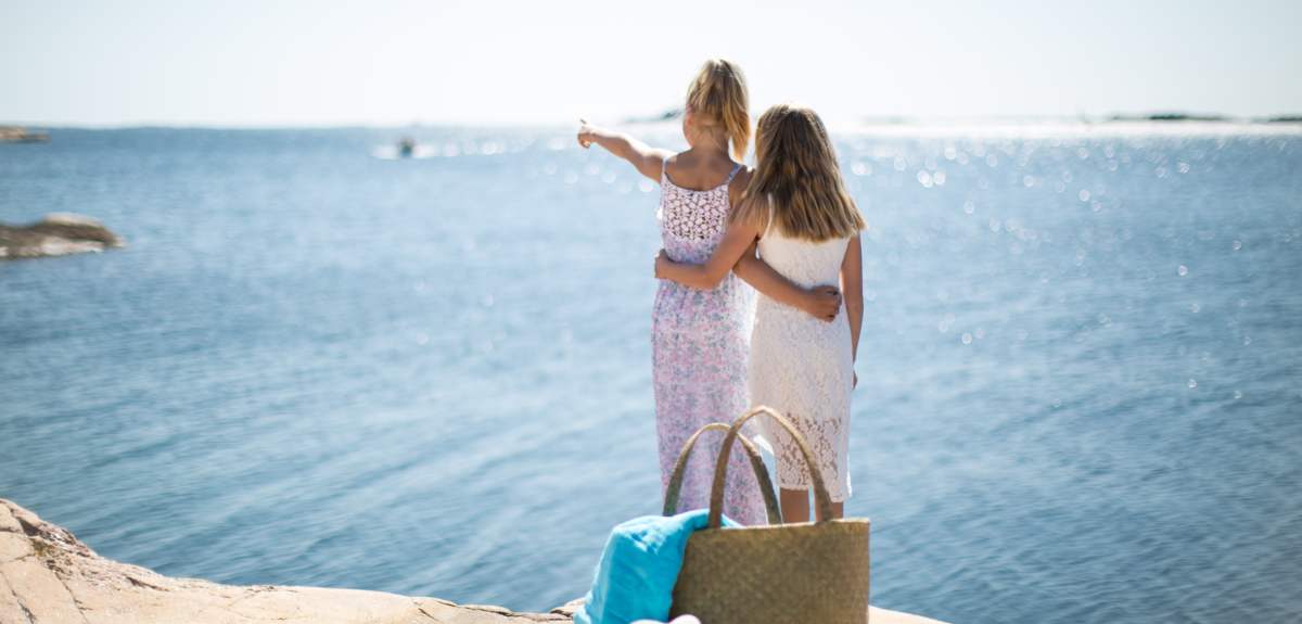 Two girls looking at the sea on a summer day in the summer paradise Southern Norway.