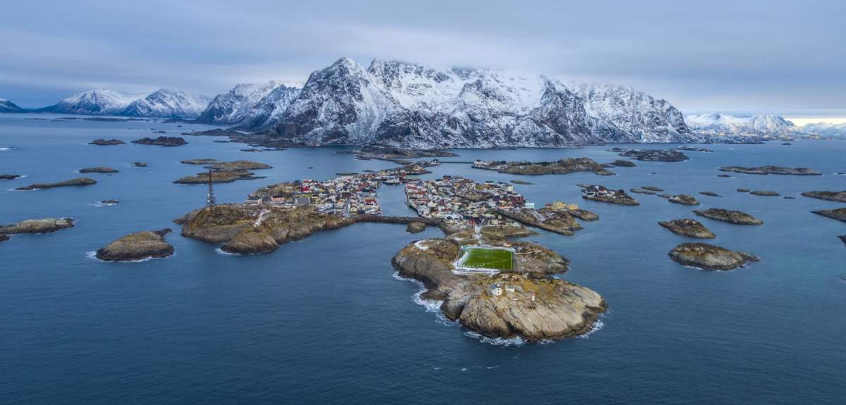 A football field on an island in Lofoten with snow-clad mountains in the horizon