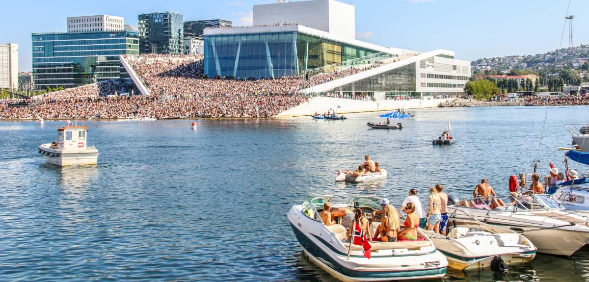 Boats in front of a crowded Oslo Opera House in summer time
