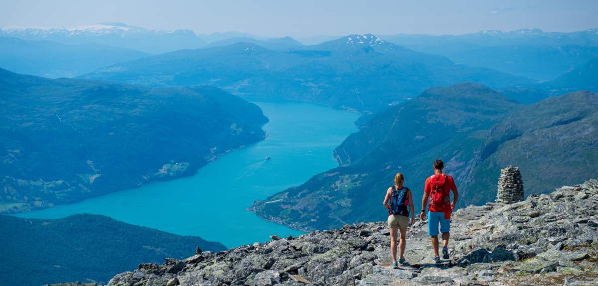 Et par går på tur i fjellet med utsikt over Nordfjord