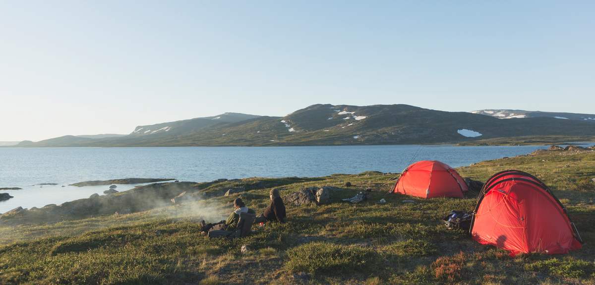 Two persons sitting next to their tents whilst enjoying the view