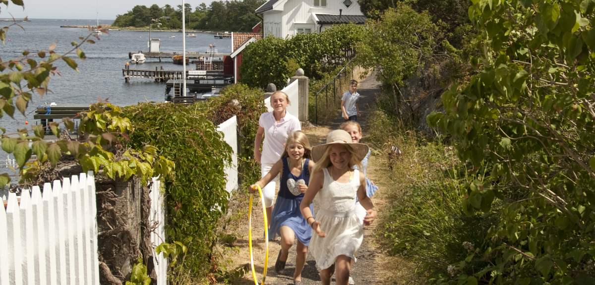 A group of children running along a white picket fence on Merdø island in Arendal, Southern Norway.