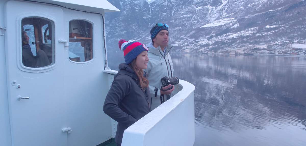 Two people standing on a boat enjoying the view of the Nærøyfjord in winter