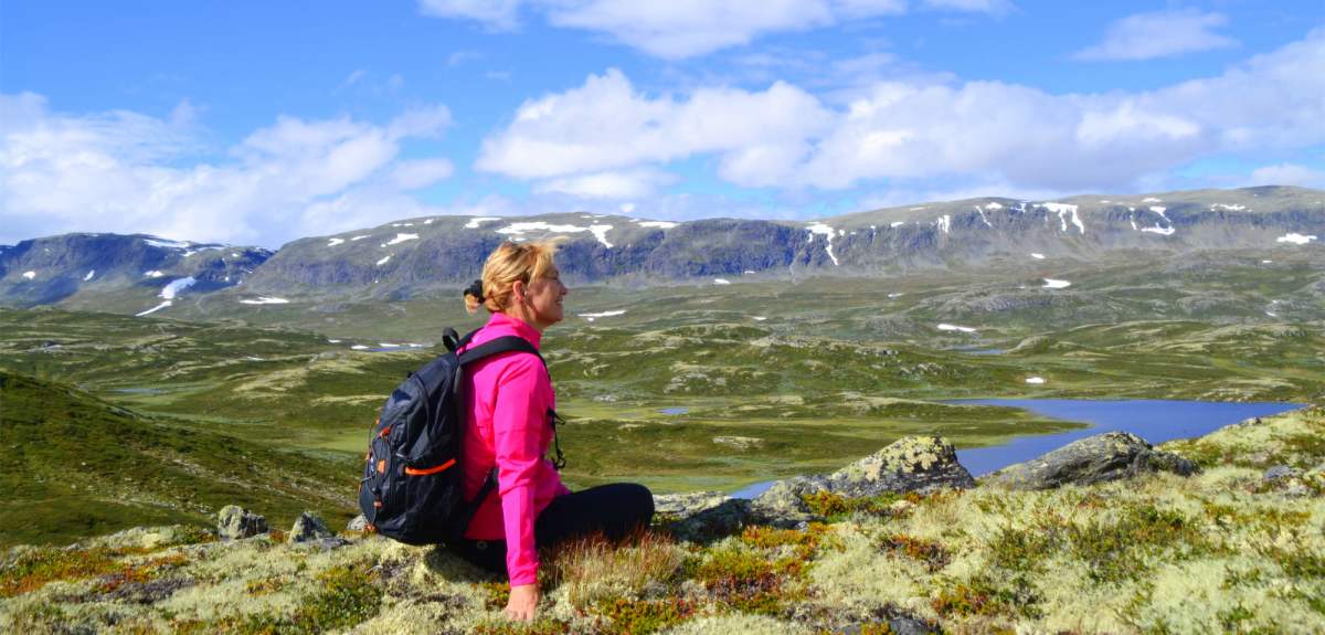 A woman sitting and enjoying the view of the mountains in Ål in Hallingdal, Eastern Norway