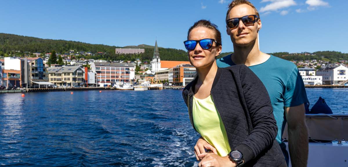A man and a woman standing on a boat in Molde in Northwest, Fjord Norway.