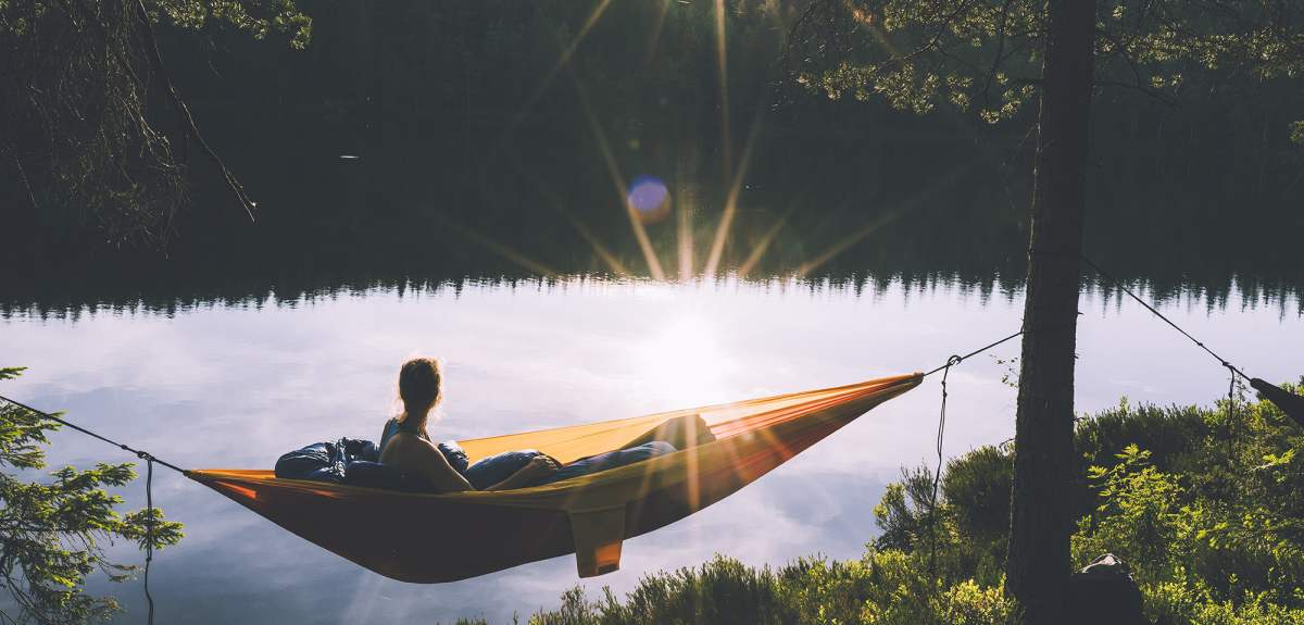 A woman relaxing in a camping hammock while during sunset in Nordmarka forest in Oslo, Eastern Norway