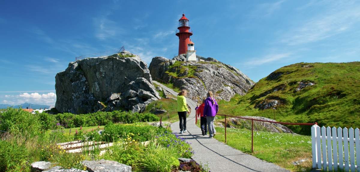 People walking towards Ona lighthouse in Møre og Romsdal, Norway