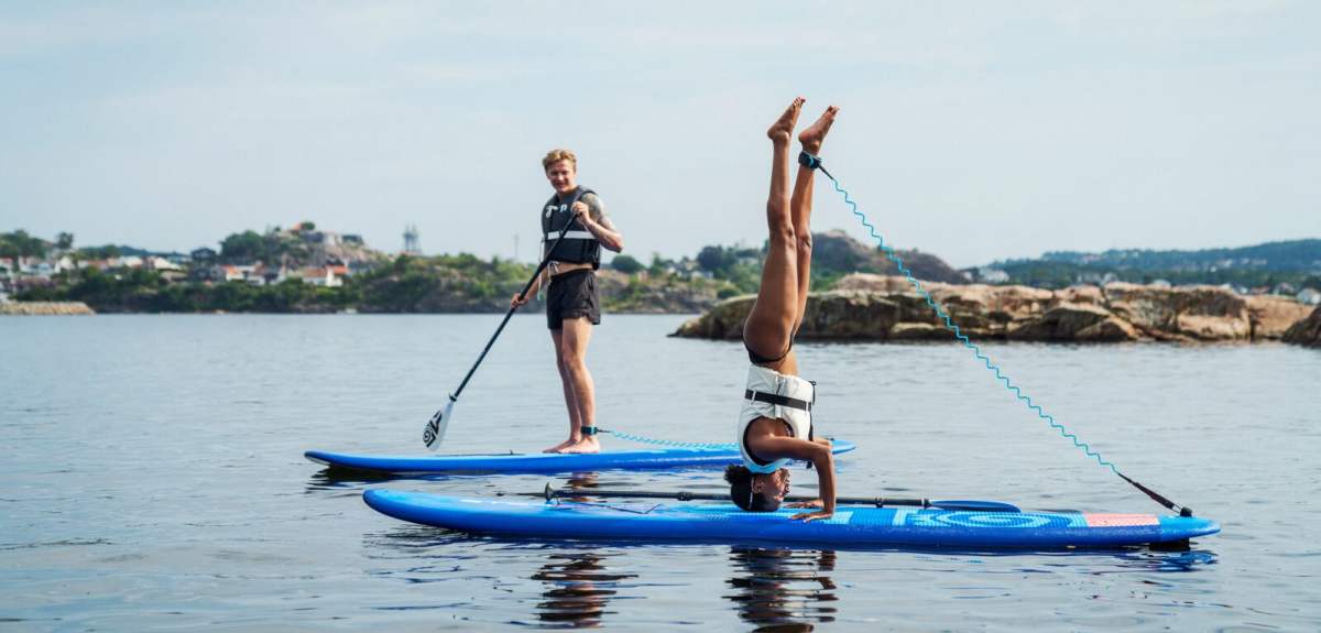 Two people are stand up paddleboarding in Southern Norway
