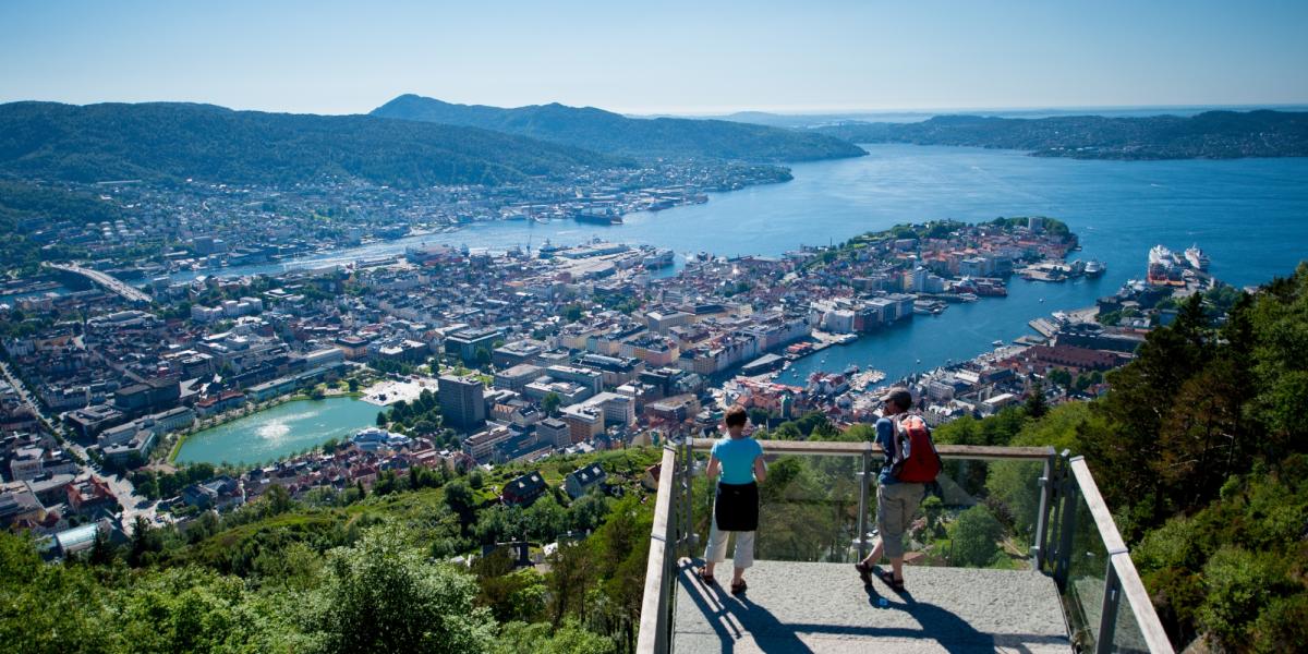 En mann og en dame nyter utsikten fra Fløyen i Bergen en sommerdag