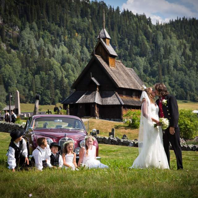 A wedding couple kisses in front of Eidsborg stave church in Telemark in Eastern Norway