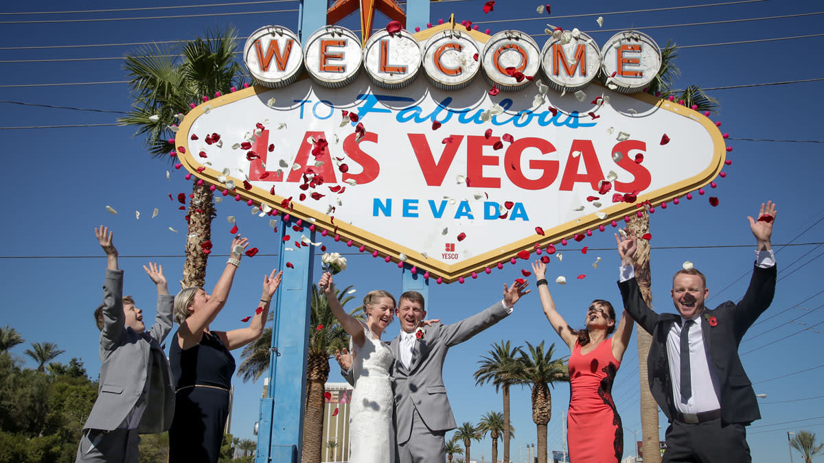 Newlyweds and wedding guests celebrating at the Welcome to Las Vegas sign