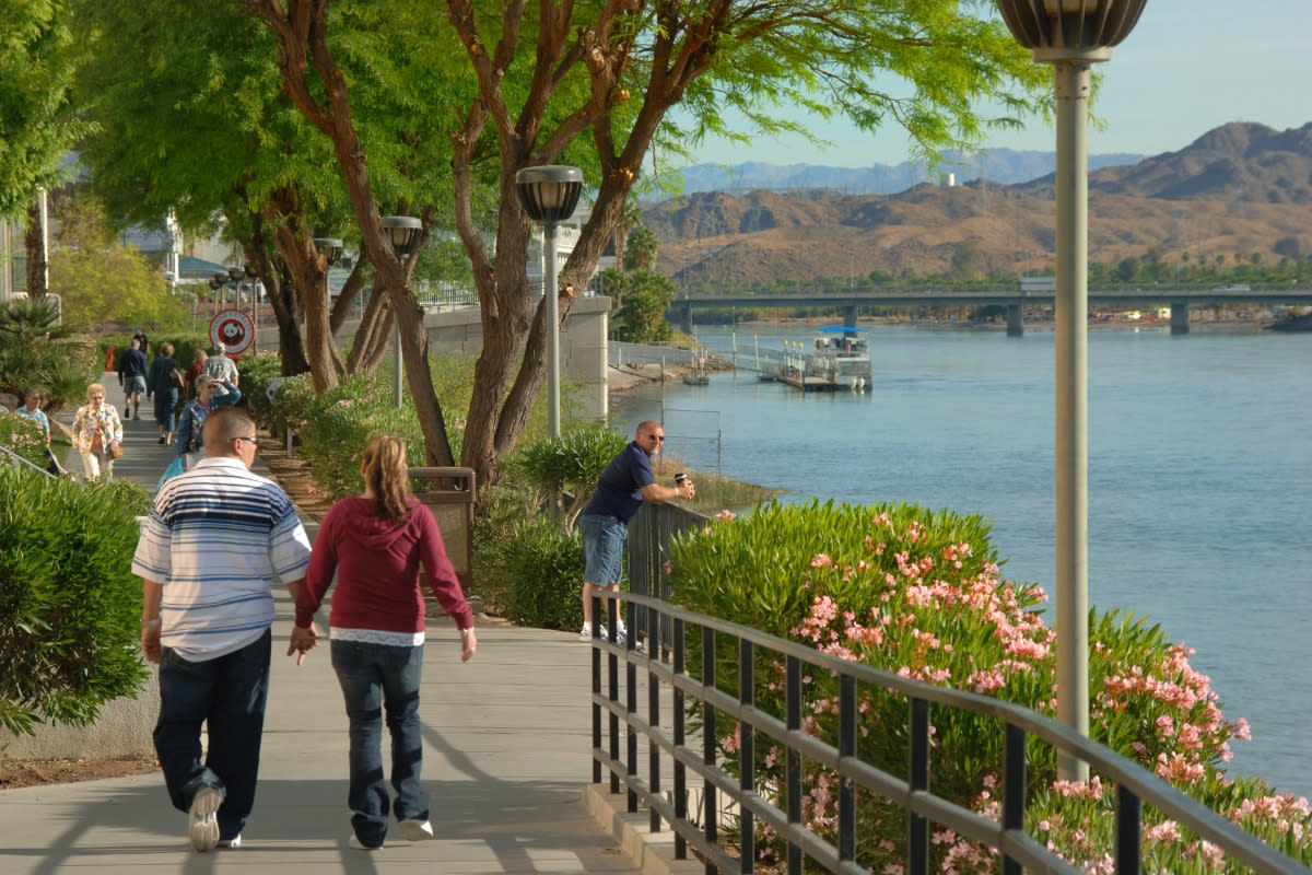 A couple walking down the Laughlin River Walk holding hands.