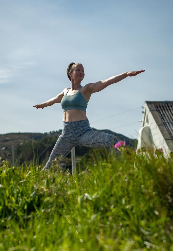 A woman, Rutt-Lovise are doing yoga, a warriors pose at Skongenes light house in Fjord Norway