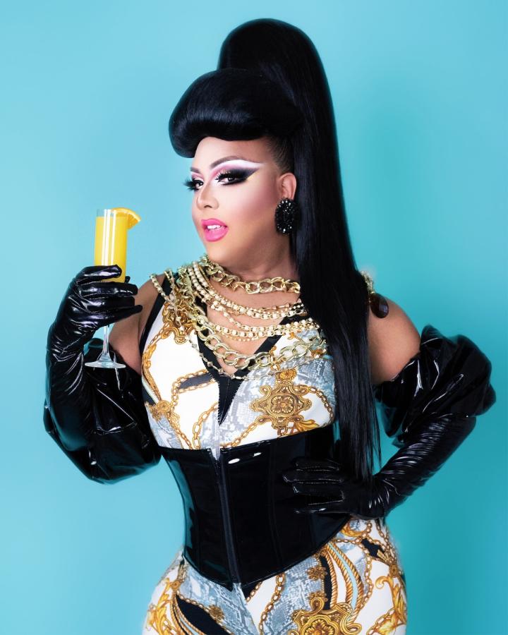 A drag queen holding a mimosa