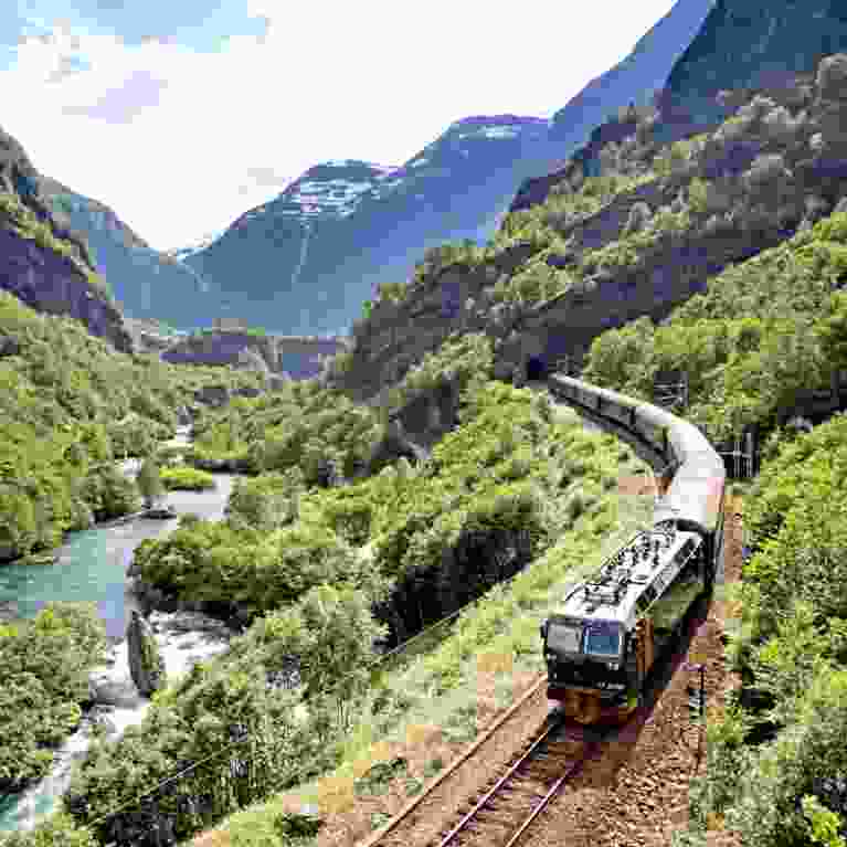 The Flåm Railway going through the landscape of green hills and spectacular mountains in Fjord Norway