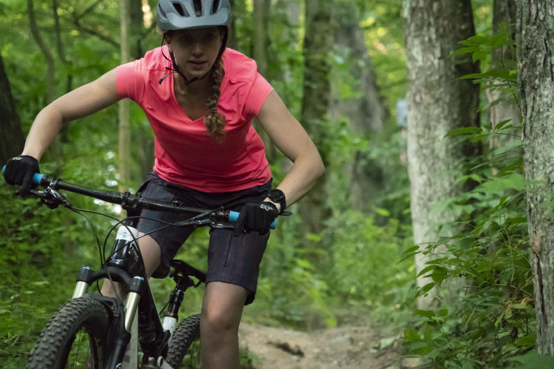 Mountain biker with pink shirt riding through a trail near Grand Rapids