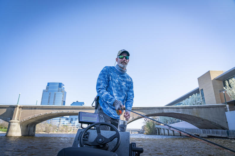 A person fishing in the Grand River in downtown Grand Rapids.