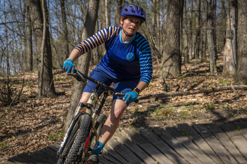 Mountain biker in blue shirt with stripes biking on a trail near Grand Rapids