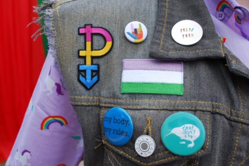 Up close view of Pride buttons on a vest of a Pride Festival attendee