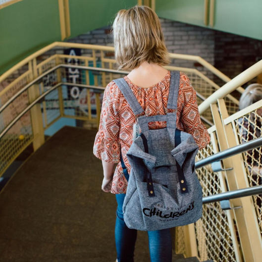 Child with backpack walking down stairs at the Grand Rapids Children's Museum