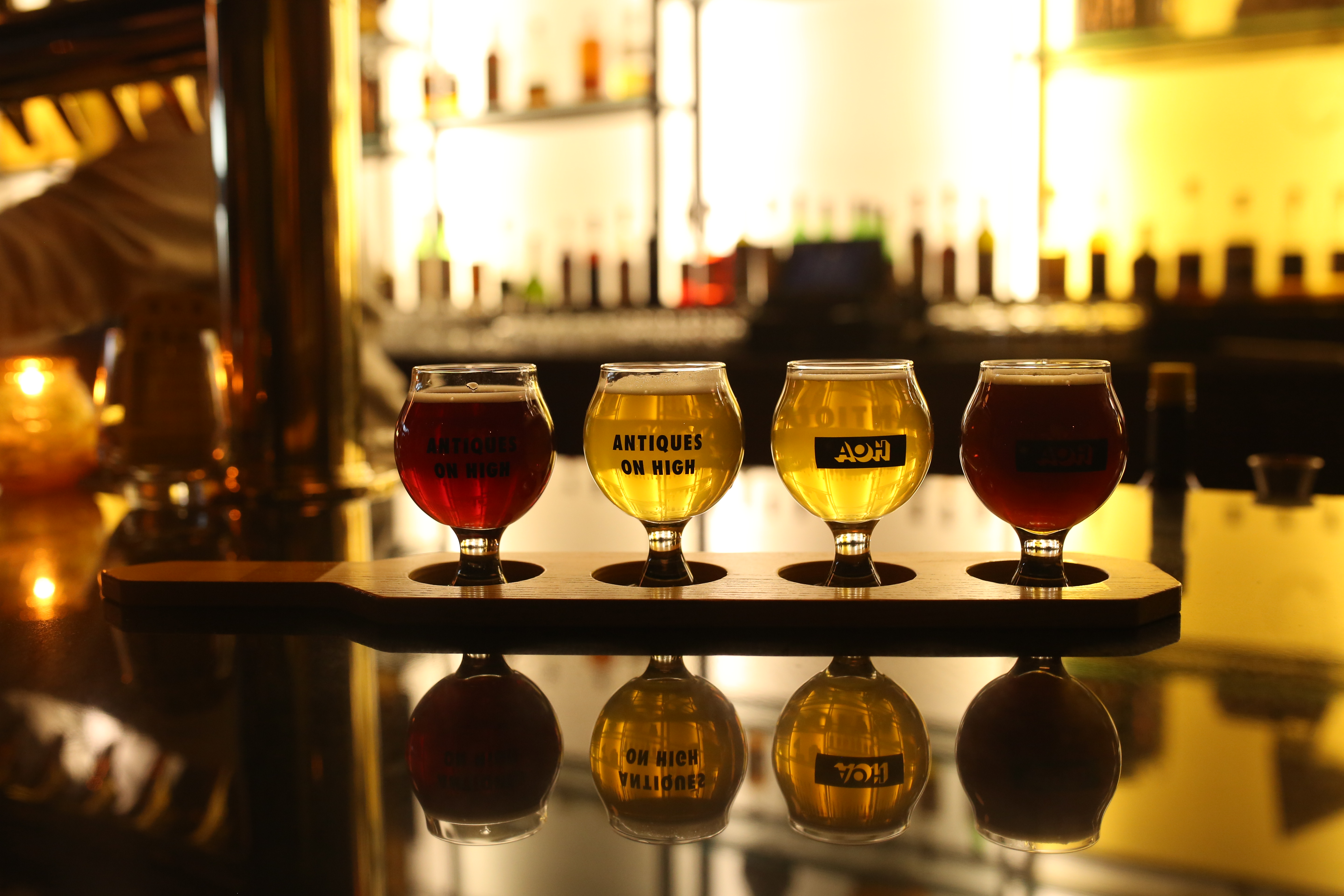 Flight of colorful sour beers on bar in dimly-lit Antiques on High