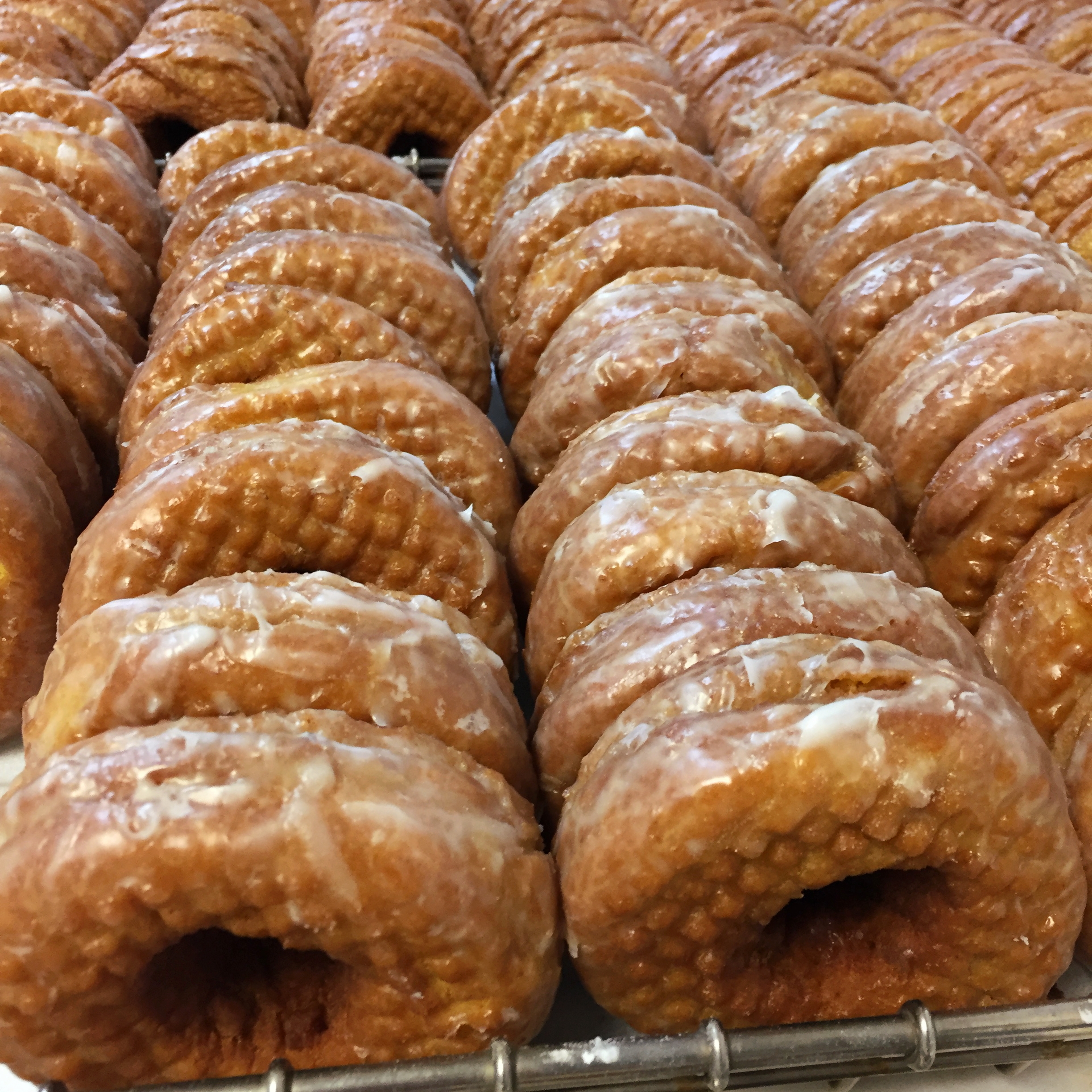 Dozens of glazed pumpkin donuts in rows