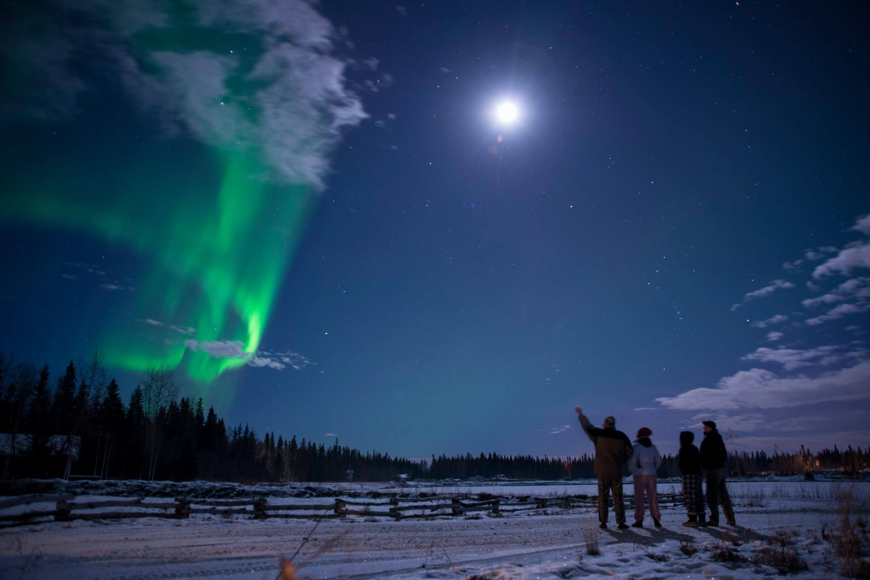 Aurora and full moon with four people watching